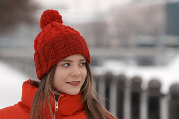 Portrait of a young girl in a red hat on a background of a winter street