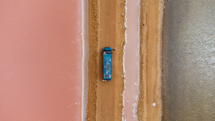 Poster - A green camper on a dirt road next to some pink salt flats