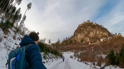 Wall Mural - Tourist couple on snow covered hiking path leading to medieval castle Burg Hochosterwitz build on massive rock on a hill in Sankt Georgen am Längsee, Sankt Veit an der Glan, Carinthia, Austria. Winter