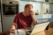 © Marko Geber - Stressed man going over bills at home