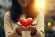 © Fotograf - A woman holding a red heart in her hands, suitable for love and Valentine's Day concepts