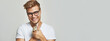 banner a smiling blond man with glasses in a white T-shirt holds an Easter bunny on a light gray background. close-up