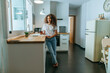 © KikoStock - Young woman in kitchen with glass of wine looking at camera