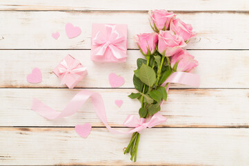Wall Mural - Pink roses with hearts and gift box on wooden background, top view.