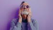 © Another vision - Elderly man with a pained expression holding his head, possibly experiencing headache or stress, against a purple background.