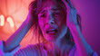 Frightened woman with a horrified expression in dim purple light, depicting fear or anxiety.
