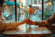 © Pinklife - A romantic moment captured as a couple sits hand in hand at a beautifully set table, surrounded by vibrant floral designs and the warm glow of natural light filtering through a nearby window