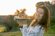 Young woman in white sweater holding a birthday cake with misplaced candles. Copy space