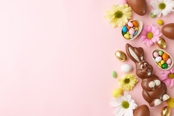 Wall Mural - Easter confections: sweetness and spring in Harmony. Top view of various chocolates, chocolate bunny, candies, spring flowers on pastel pink background with space for promotions or greetings