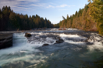 View of the Nymph Falls Waterfall looking up the Puntledge River on an autumn day.