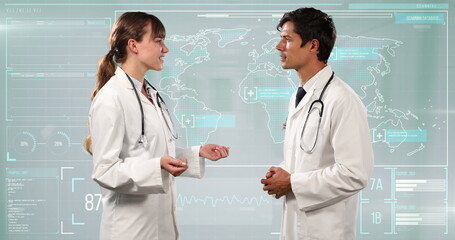 Wall Mural - Caucasian male and female doctor taking to each other against data processing in background