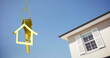 Image of golden house keys and house shaped key fob hanging over a house and blue sky 4k
