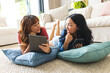© Wavebreak Media - Biracial female friends relax at home using tablets