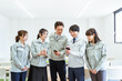 © buritora - 工場・工務店などの中小企業でスマホを見ながら同僚と談笑作業着を着た従業員・スタッフ（ビジネス）