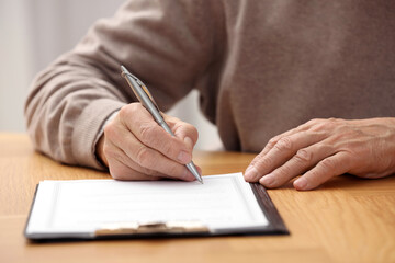 Poster - Senior man signing Last Will and Testament at wooden table indoors, closeup