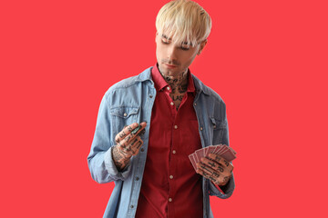 Wall Mural - Tattooed young man with poker chips and cards on red background