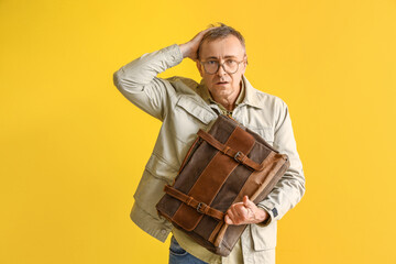 Wall Mural - Stressed mature man with briefcase on yellow background. Deadline concept