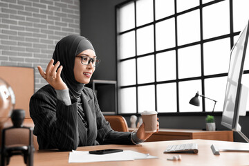 Sticker - Muslim businesswoman with cup of coffee working at table in office