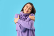 Beautiful young happy woman hugging herself on blue background