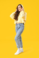 Pretty young woman in stylish hoodie on yellow background