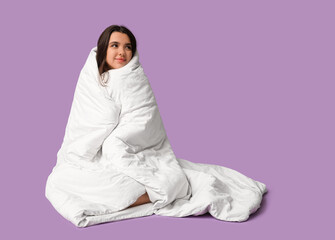 Canvas Print - Beautiful young happy woman wrapped in blanket sitting on purple background