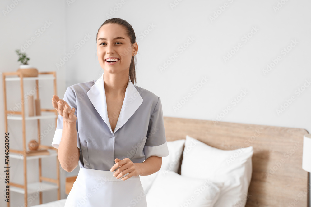Young chambermaid smiling in bedroom