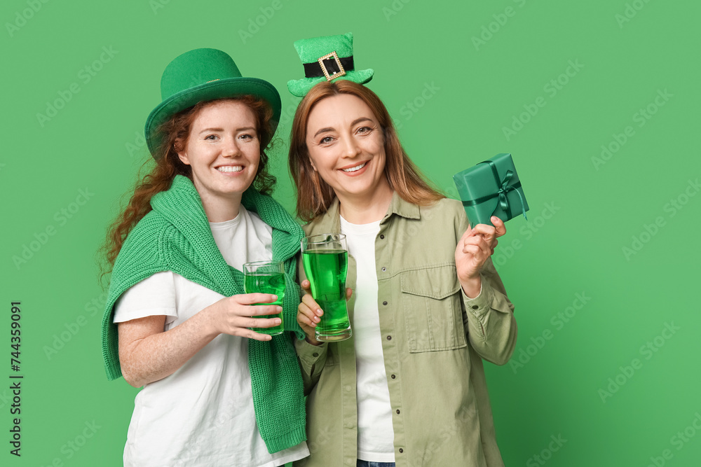 Beautiful women with beer and gift on green background. St. Patrick's Day celebration