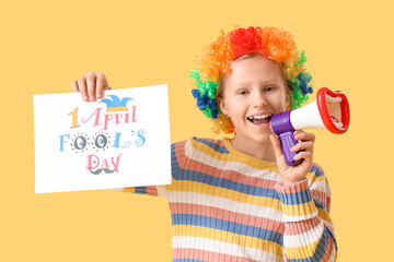 Wall Mural - Funny little girl in clown wig with megaphone and card on yellow background. April Fools' Day celebration