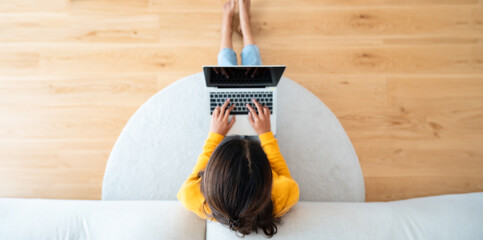 Top view of young Asian woman sitting on the floor and working on computer laptop