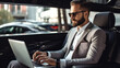 A handsome executive uses his laptop while enjoying the comfort of a luxury car.