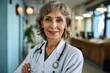 Portrait of smiling older senior female professional doctor physician pediatrician wearing white robe with stethoscope around neck standing in modern private clinic hospital, Generative AI