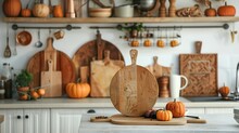 Wooden Cutting Boards, Other Cooking Utensils And Pumpkins On White Countertop In Kitchen