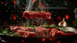 Fototapeta Przestrzenne - Striploin steaks of marbled beef fall in slow-motion, camera effect. Drops of hot oil, chili, black pepper, rosemary, garlic above an extremely hot grill pan. Dark background. Realistic.