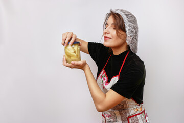 A beautiful girl holds homemade jam in her hands. Housework concept.