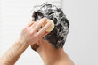 © New Africa - Man washing his hair with solid shampoo bar in shower, closeup