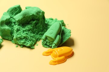 Poster - Bright kinetic sand and plastic toys on beige background, space for text