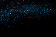 Blue sparkles or glitter over black cosmic abstract background.