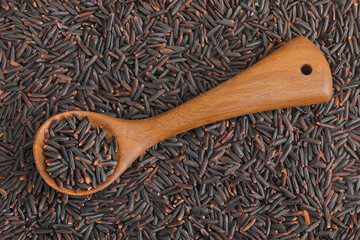 Poster - Black rice in a wooden spoon as a background. Top view. Flat lay