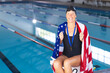Proud athlete wrapped in the American flag at a pool with a medal