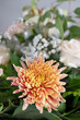 Details of a large bridal table floral centerpiece with focus on a large orange chrysanthemum, elegant flower arrangement brightening up the space: a restaurant or a reception area for the wedding day