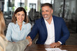 © Stock 4 You - Mature Latin businesspeople of woman and European business man shaking hands with colleagues, partners or employees, signing a contract. Group of people satisfied with results of team work together.