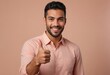 © natakot - A young man in a salmon shirt with a beaming smile gives a thumbs up, exuding charisma and a friendly demeanor.