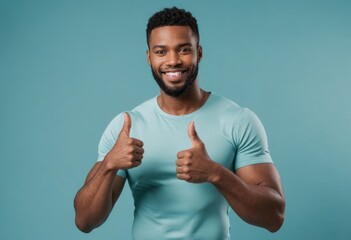 Wall Mural - A friendly man in a teal t-shirt smiling at the camera, making the thumbs up sign with both hands, exuding approachability and positivity.