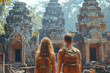 Back view of young couple tourists with backpacks looking at ruins of ancient asian temple