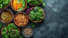Variety of nutrient-rich superfoods in wooden bowls, including fresh leafy greens, nuts, and grains on a dark textured background.