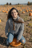Fototapeta Krajobraz - Young woman sitting on a pumpkin during the fall season
