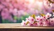 beautiful pink sakura flowers above a wooden table against a blurred spring background in pastel pink colors shallow dof