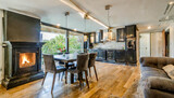Fototapeta Przestrzenne - Beautiful open plan matte black kitchen and dining area with fireplace