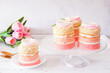 Spring mini cakes with buttercream rose. Table scene with a white wood background. Pink layers with flower topping.