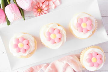 Wall Mural - Plate of pink spring flower cupcakes. Top view table scene with a white wood background.